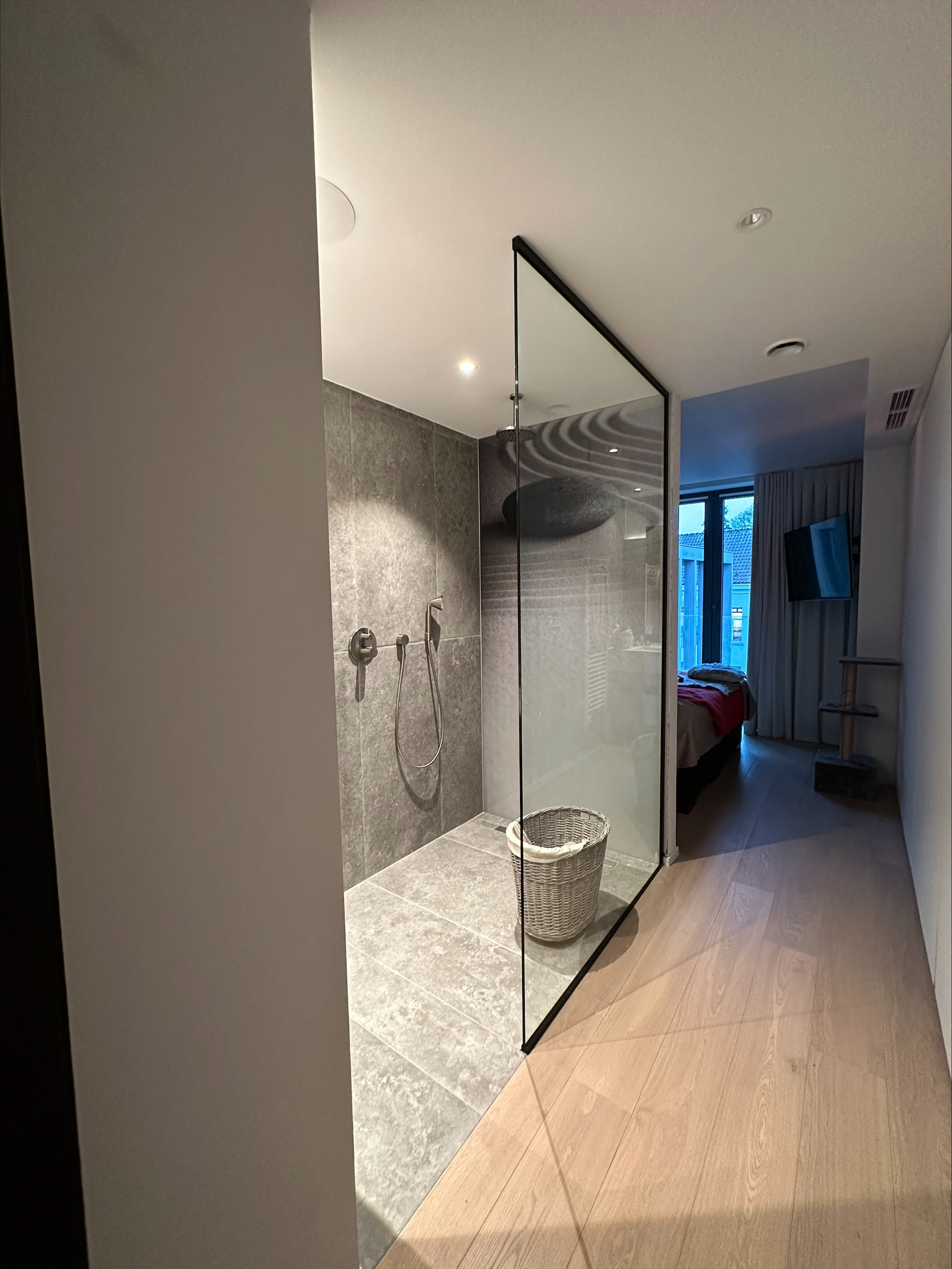 Een inloopdouche met glazen wand creëert een ruimtelijk en luxueus gevoel in de badkamer.