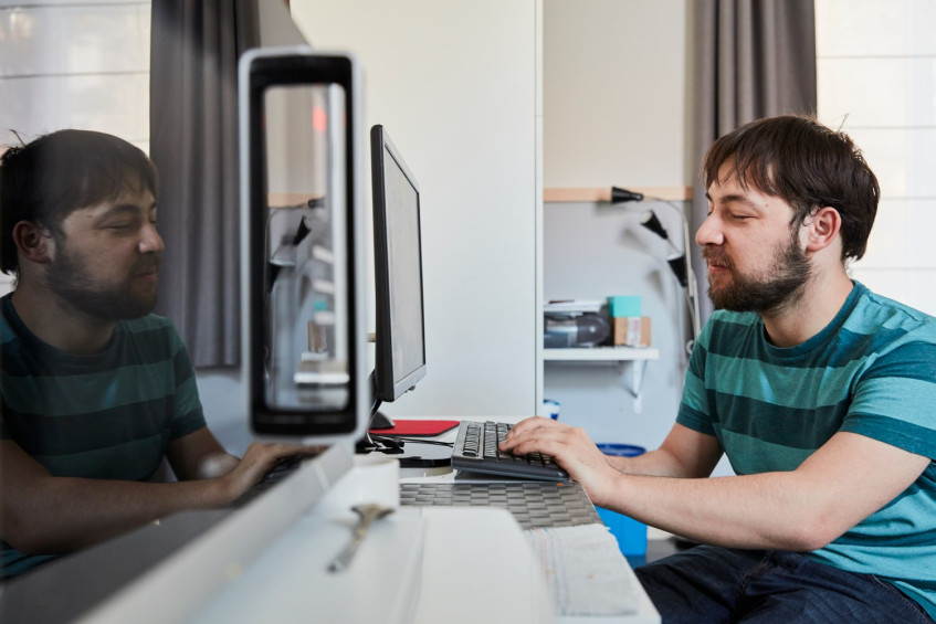 Slechtziende man met gestreepte T-shirt bezig aan computer
