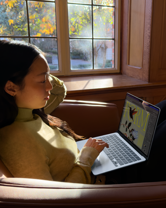 Iemand zit in een fauteuil en werkt op een MacBook Air