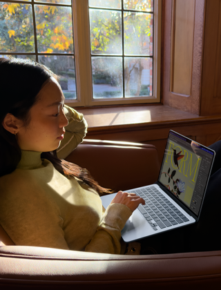 Iemand zit in een fauteuil en werkt op een MacBook Air
